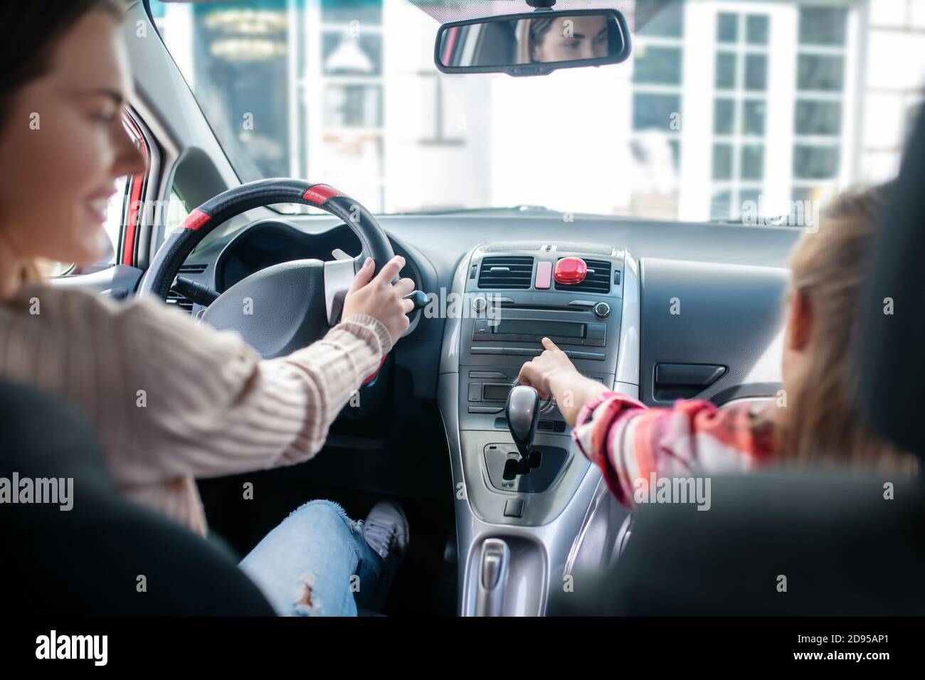 Mädchen zeigt auf Armaturenbrett, sitzen im Auto mit ihrer Mutter Stockfoto