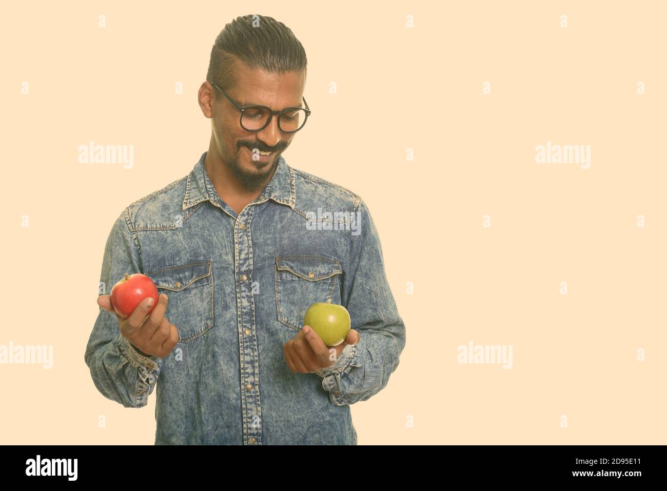 Junge glücklich indischen Mann die Wahl zwischen roter und grüner Apfel Stockfoto