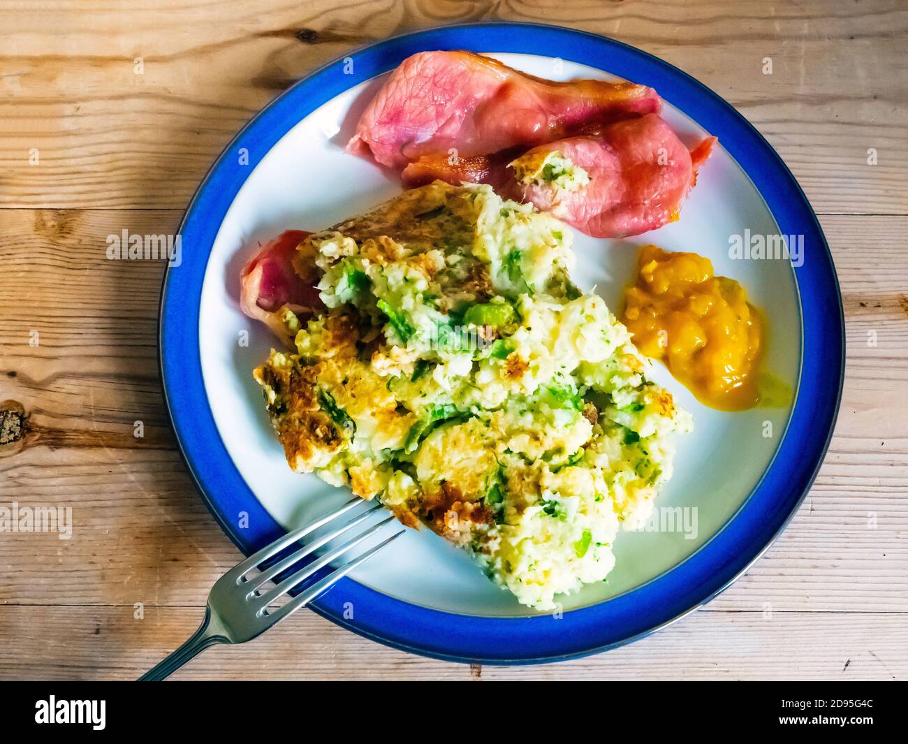 Bubble und Squeak ein traditionelles Gericht von links über gemacht Kartoffeln und Gemüse hier serviert mit knackigem gebratenem Speck und Piccalli Senf Gurke auf a b Stockfoto