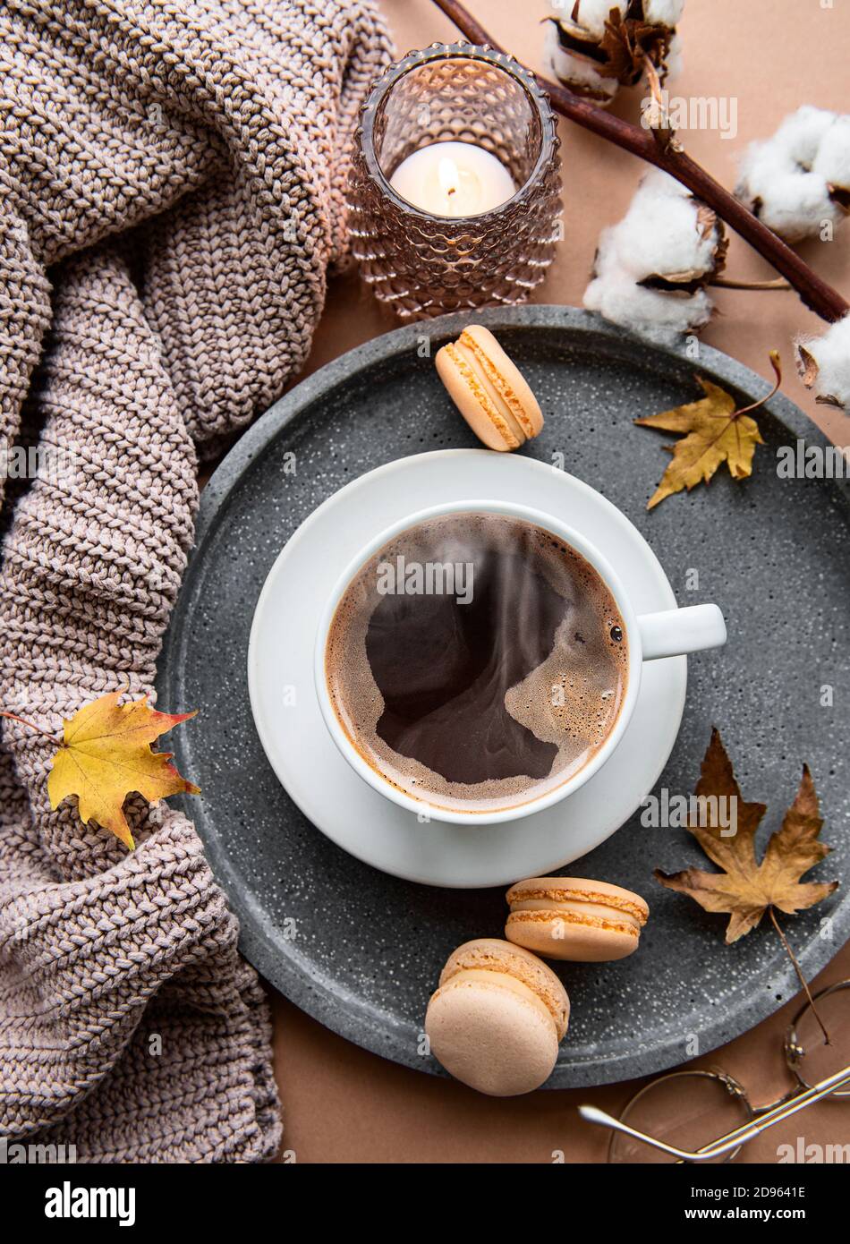 Schöne und romantische Herbstkomposition mit Tasse Kaffee, warmer Decke, dekorativ gestreiften Kürbissen, Kerzen und Herbstblättern. Gemütlicher Morgen. Hyg Stockfoto