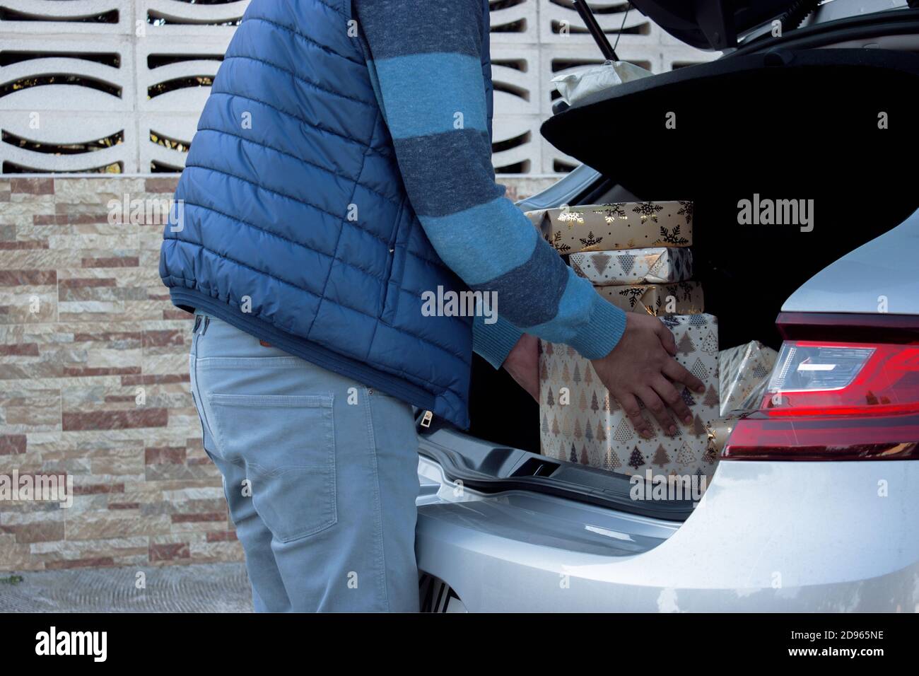 Ein Mann nimmt aus dem Auto Weihnachtsgeschenke, die er gerade gekauft hat, um unter den Weihnachtsbaum zu Hause setzen. Weihnachten photograhy Weihnachten Verbraucher. Stockfoto