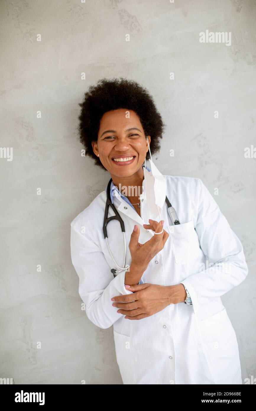 Weibliche afroamerikanische Arzt tragen weiße Uniform und Abheben Gesichtsmaske im Krankenhaus Stockfoto