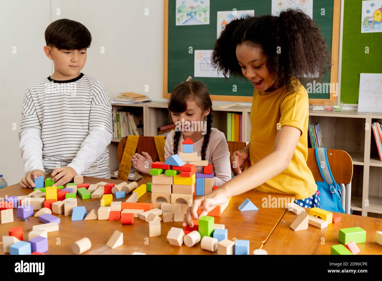 Gruppe von multiethnischen Schulfreunden mit Spielzeugblöcken im Klassenzimmer, Bildung, Lernen, Teamarbeit. Kinder spielen mit Holzblöcken im Klassenzimmer Stockfoto