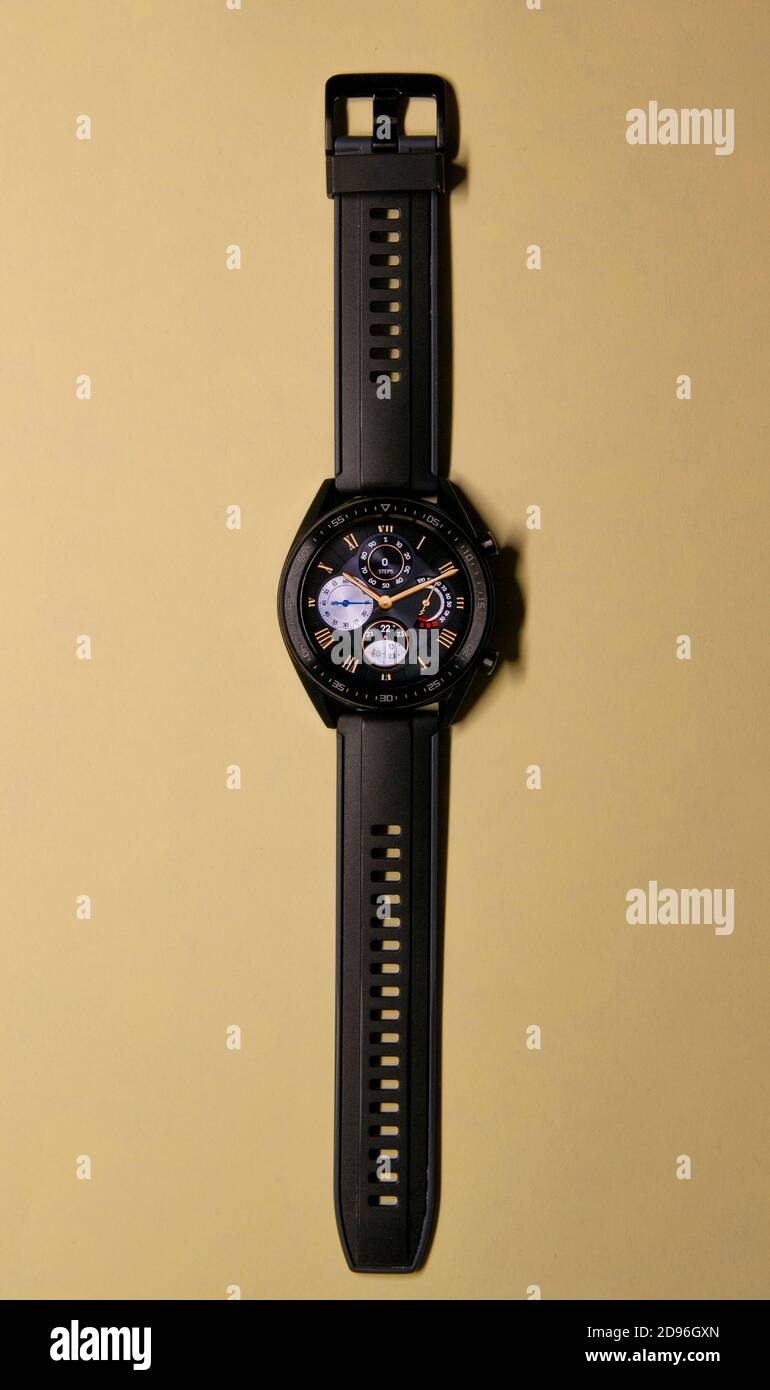 Nahaufnahme einer schwarzen Smartwatch auf goldenem Hintergrund, ähnlich einem Zifferblatt. Technologie und Eleganz Konzept. Vertikale Fotografie. Speicherplatz kopieren Stockfoto