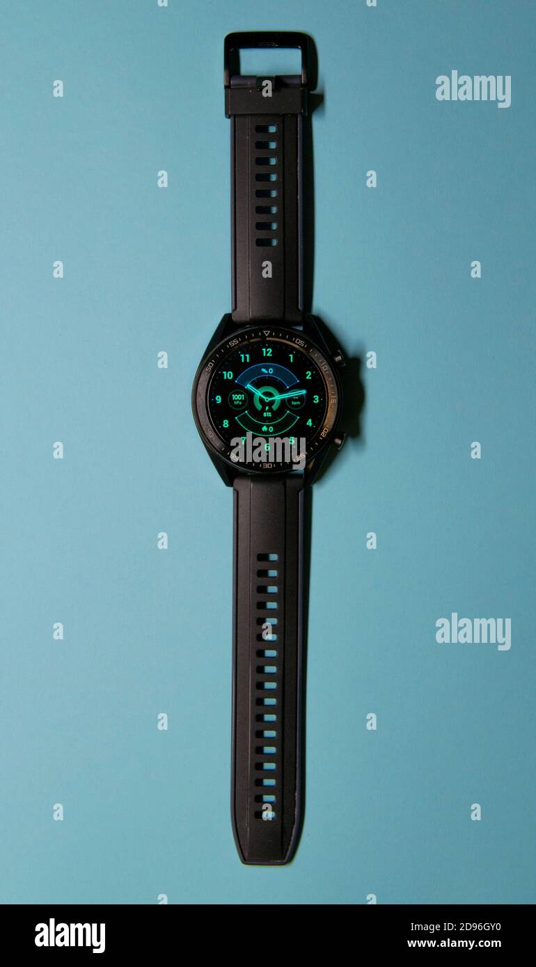 Nahaufnahme einer schwarzen Smartwatch auf blauem Hintergrund, ähnlich einem Ziffernblatt. Technologie und Eleganz Konzept. Vertikale Fotografie. Speicherplatz kopieren Stockfoto