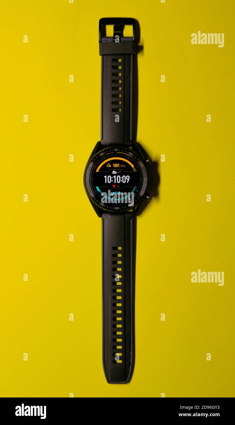 Nahaufnahme einer schwarzen Smartwatch auf gelbem Hintergrund, ähnlich einem Zifferblatt. Technik und Sportkonzept. Vertikale Fotografie. Speicherplatz kopieren Stockfoto