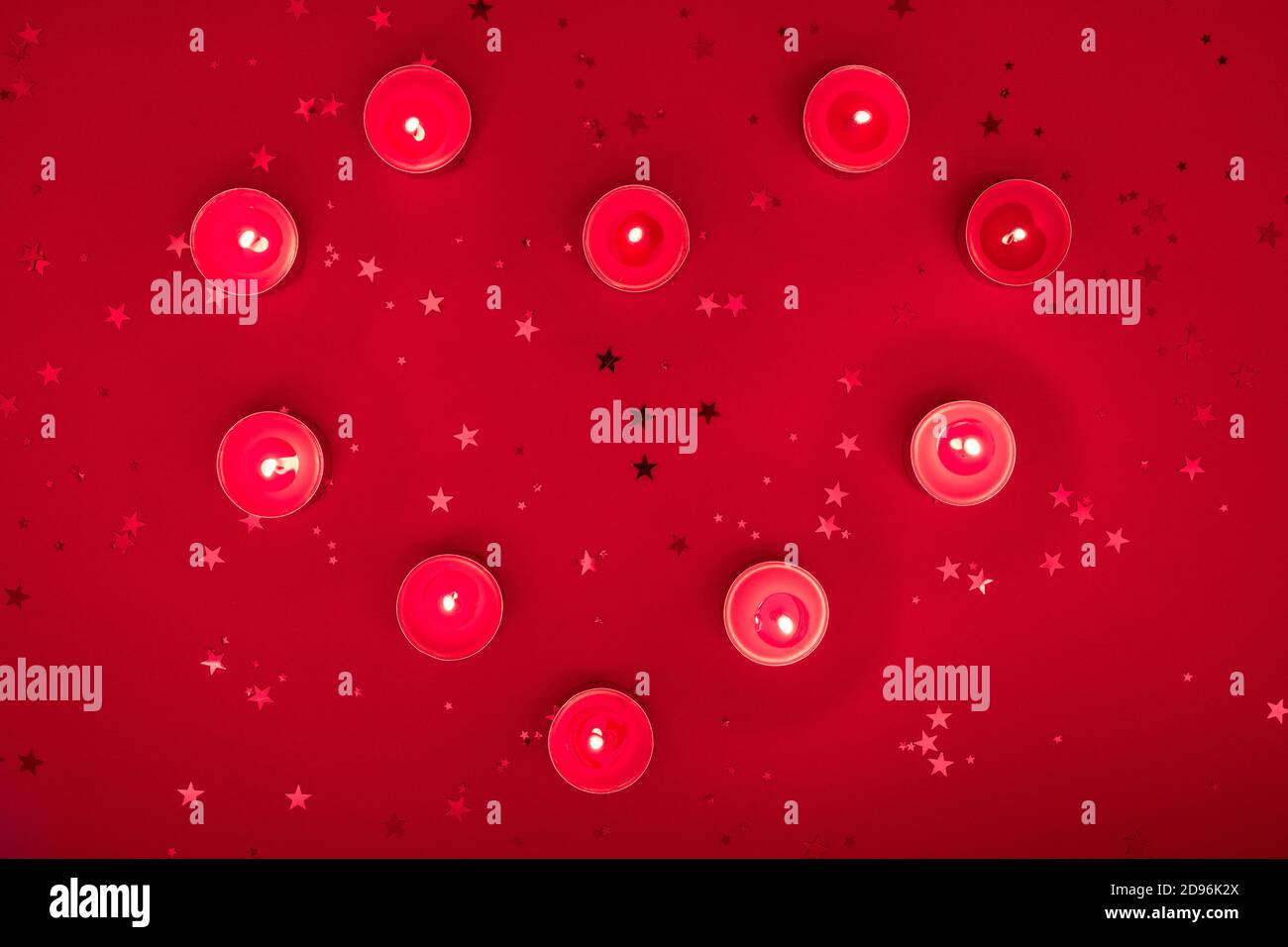 Weihnachtsabend oder Valentinstag Komposition aus brennenden Kerzen, Glitzer auf roter Oberfläche. Frohe weihnachten und glückliches Neues Jahr 2021, glücklich Stockfoto
