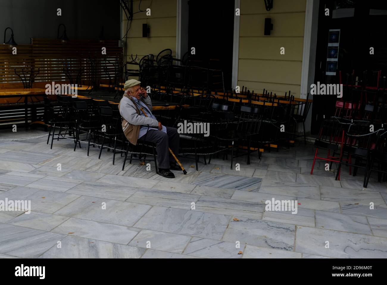 Athen, Griechenland. November 2020. Ein älterer Mann sitzt auf einem Stuhl eines geschlossenen Cafés. Ab heute die neuen Maßnahmen angekündigt Samstag von der Regierung, um die schnelle Ausbreitung von COVID-19 zu bekämpfen statt Maßnahmen schließen Bars, Restaurants, Cafés, Fitness-Studios und Museen. Kredit: Michael Varaklas/Alamy Live Nachrichten Stockfoto