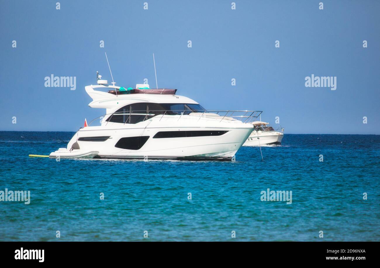 Eine Luxusyacht, die mit klarem Blau auf dem Meer segelt Himmel und Horizont im Hintergrund sichtbar Stockfoto