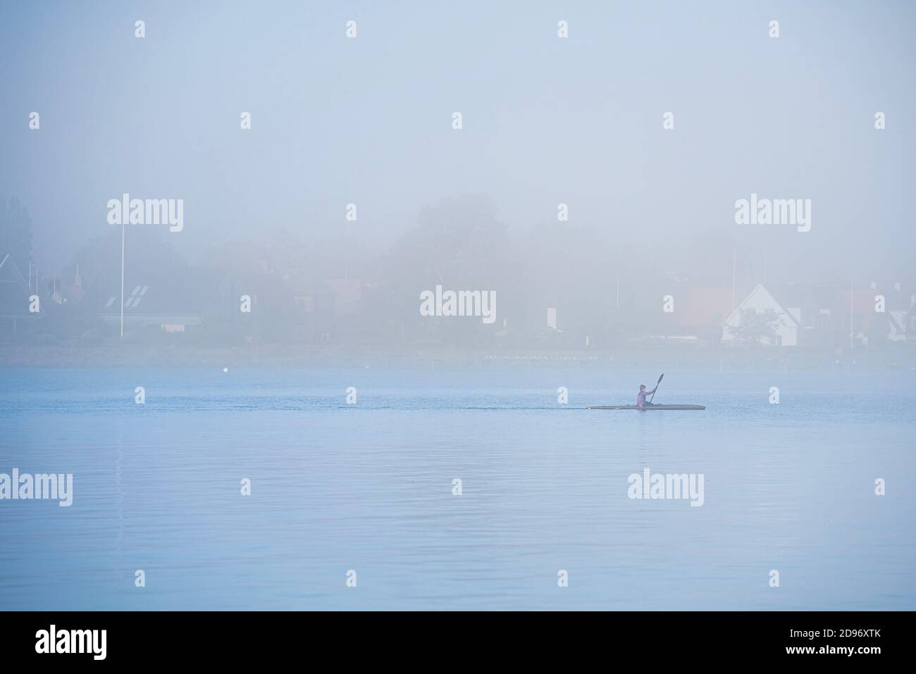 Halten Sie sich fit Rudern ein Kanu im Nebel an einem düsteren Tag. Gesunder Lebensstil Kajakfahren im Nebel. Ein begeisterter Kanufahrer auf einer ruhigen, ruhigen Ostsee. Dragor Stockfoto