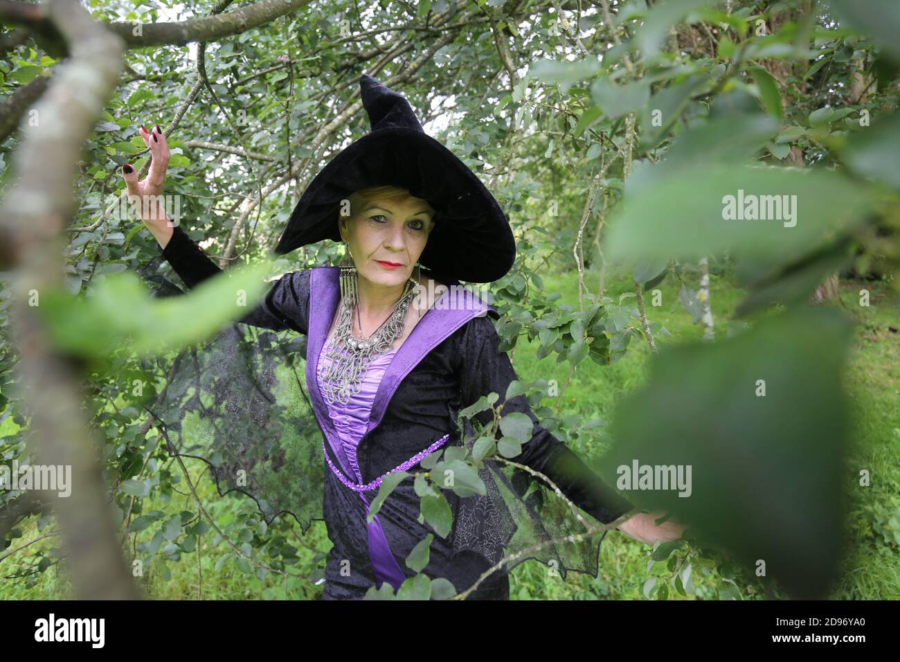 Ältere Frau gekleidet als Hexe mit Tarot-Karten & Kristallkugel vor dem zerstörten Gebäude Stockfoto