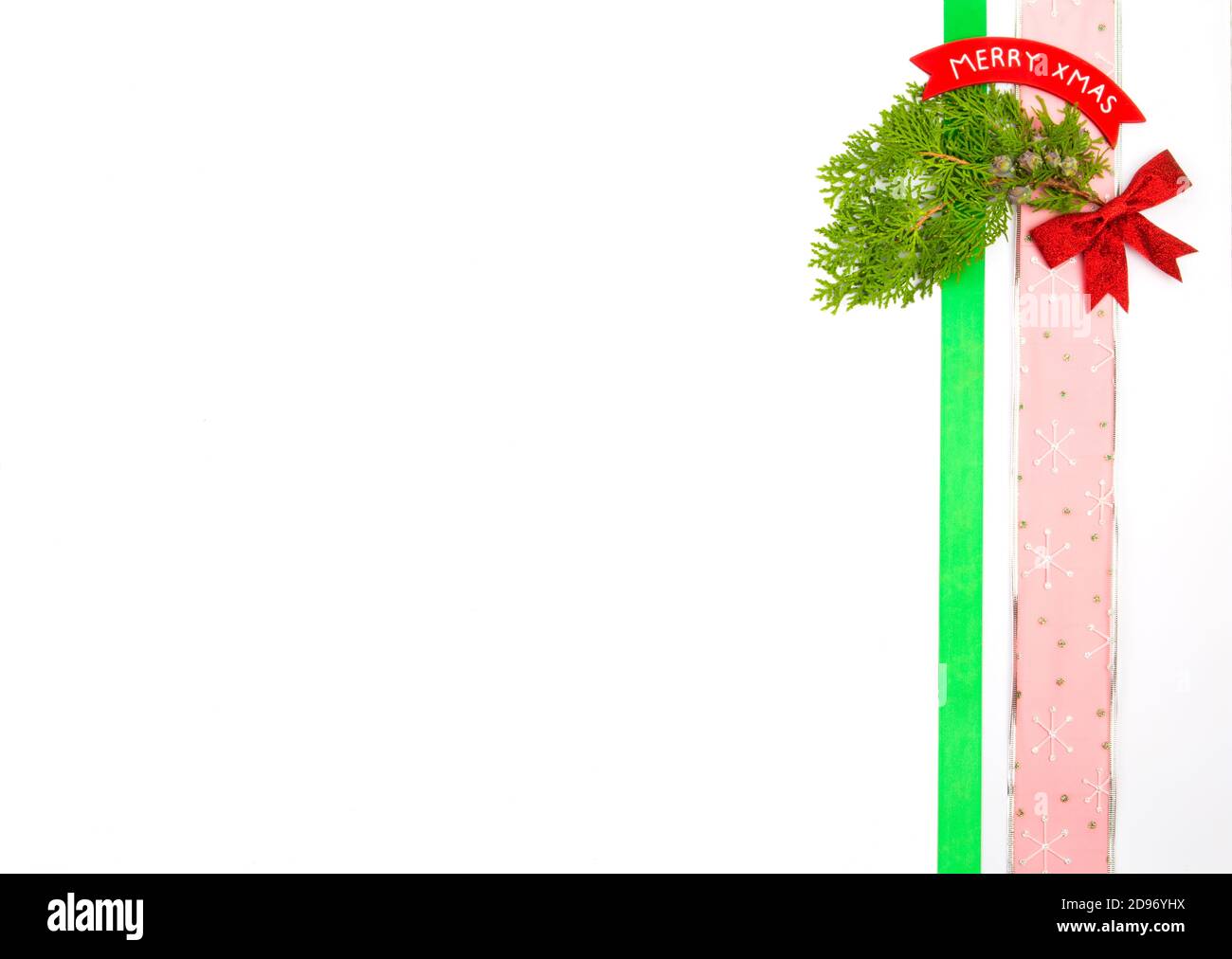 Weihnachtsdekorationen vertikal auf der Seite des Bildes mit Copyspace auf weißem Hintergrund platziert, Kiefernzweige, Band, Bogen und fröhliche weihnachten s Stockfoto