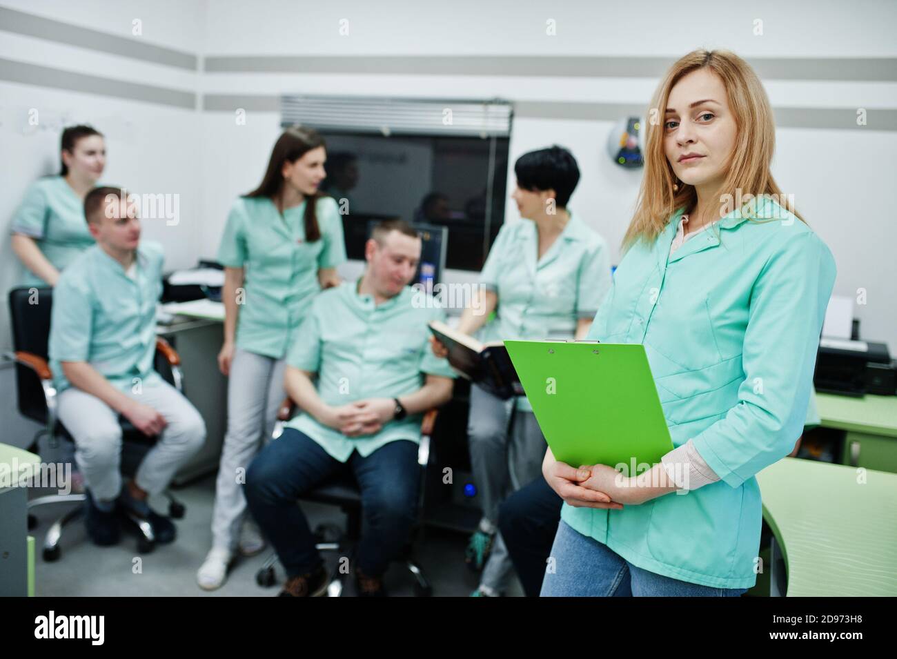 Medizinisches Thema .Porträt der weiblichen Ärztin mit Zwischenablage gegen Gruppe von Ärzten Treffen in der mrt-Büro im diagnostischen Zentrum im Krankenhaus. Stockfoto