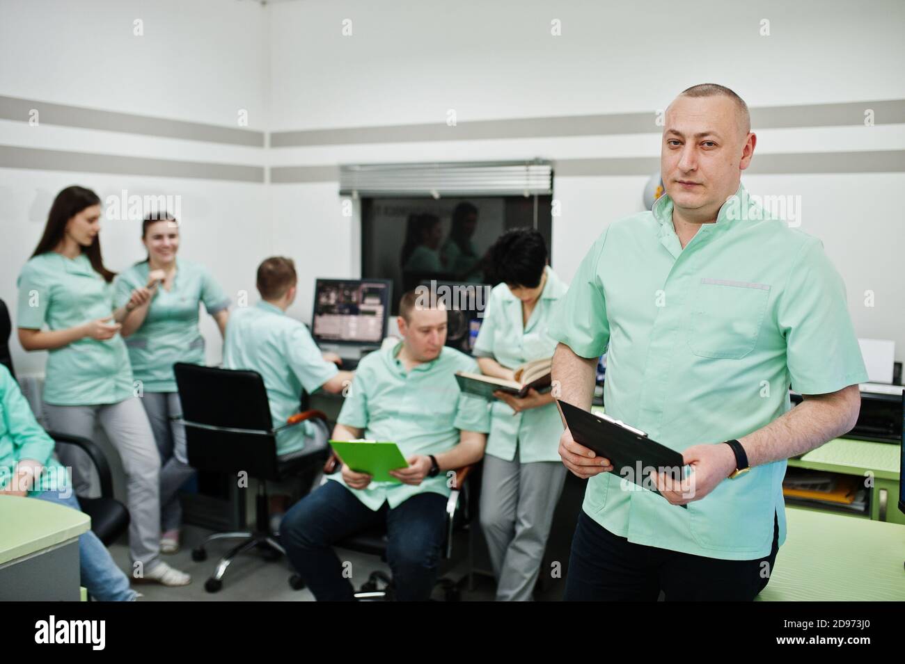 Medizinisches Thema .Porträt des Arztes mit Zwischenablage gegen Gruppe von Ärzten Treffen im mrt-Büro im Diagnostikzentrum im Krankenhaus. Stockfoto