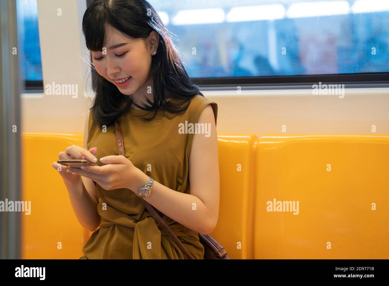 Junge asiatische Frau, die mit dem Zug und Smartphone unterwegs ist. Stockfoto