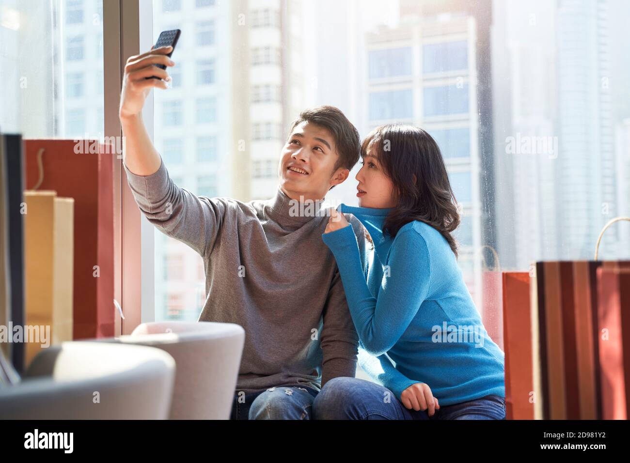 Glückliches junges asiatisches Paar, das ein Selfie im Hotelzimmer macht Nach dem Einkaufen in der Stadt Stockfoto