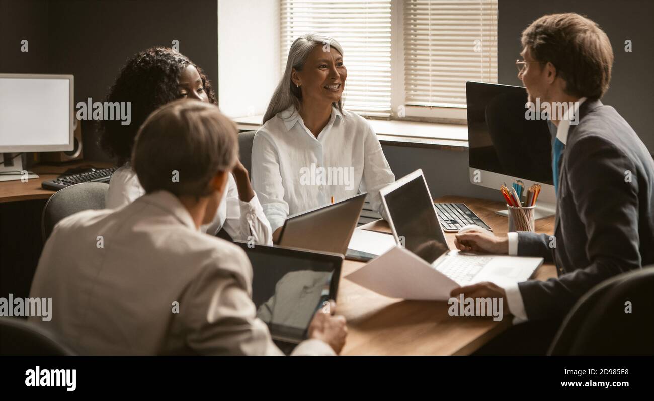 Brainstorming-Team von Büromitarbeitern. Seitenansicht der verschiedenen Gruppen, die am Bürotisch arbeiten. Teamwork-Konzept Stockfoto