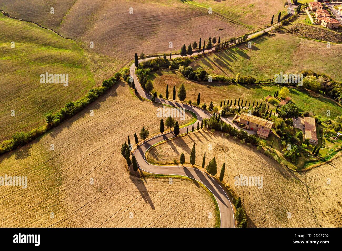 Luftaufnahme von kurvenreichen Straßen und goldenen Feldern in Pienza Toskana Italien. Stockfoto
