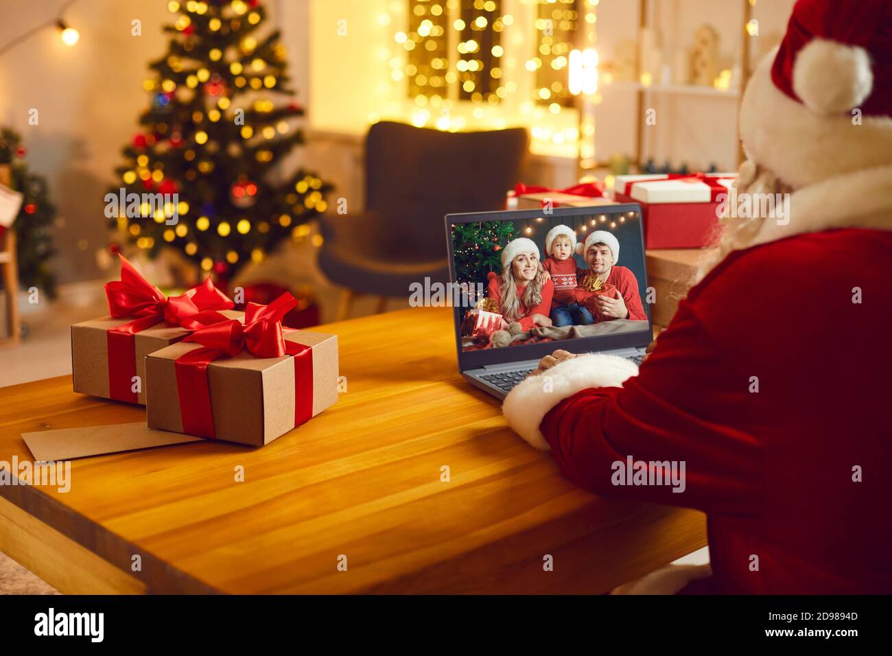 Weihnachtsmann in rotem Kostüm Kommunikation mit Enkeln und Familie online Auf einem Laptop Stockfoto