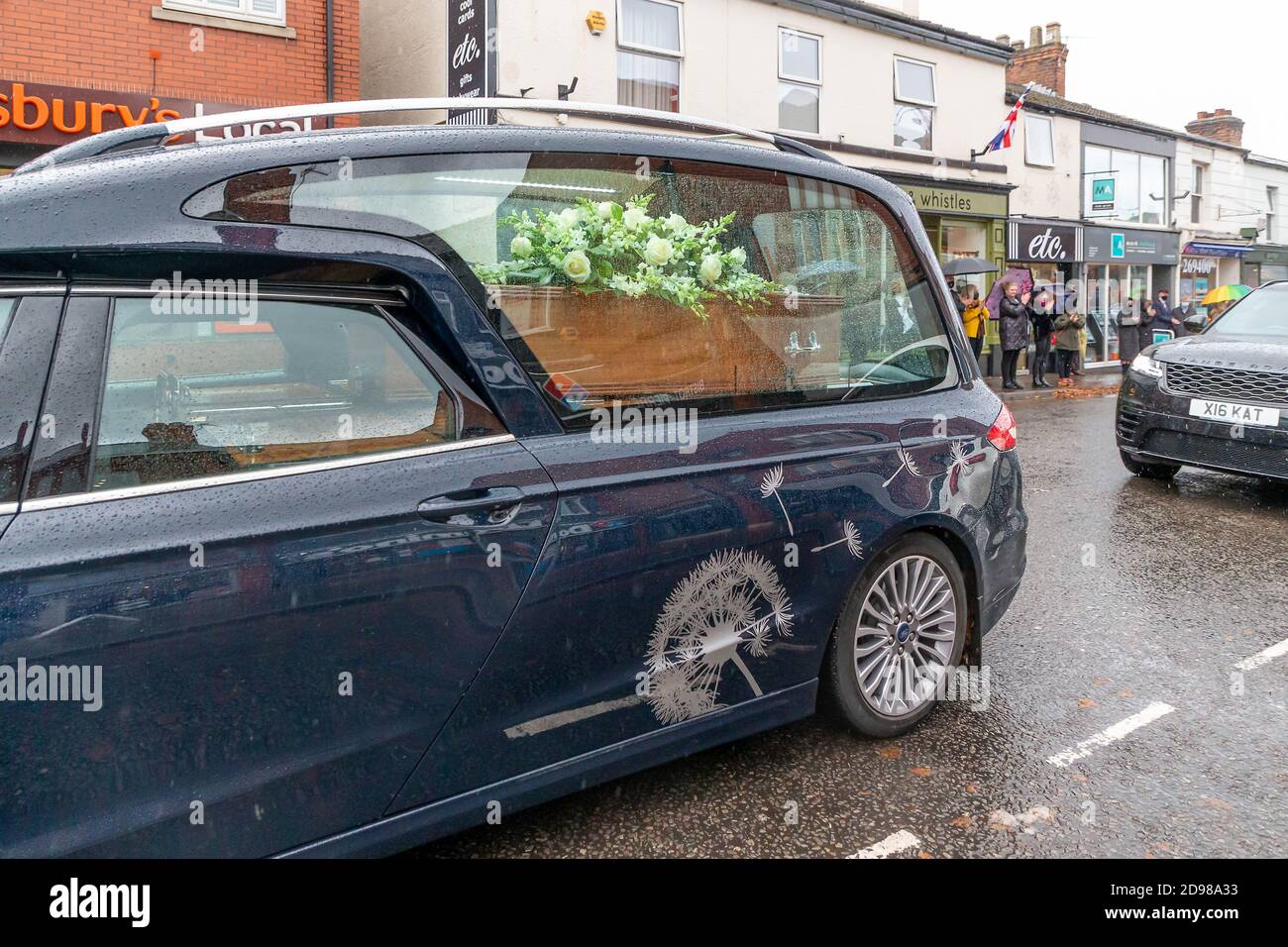 Freunde, Familie und lokale Händler säumen die Straßen, um dem Leichenschauhaus eines lokalen Händlers ihren Respekt zu zollen Stockfoto