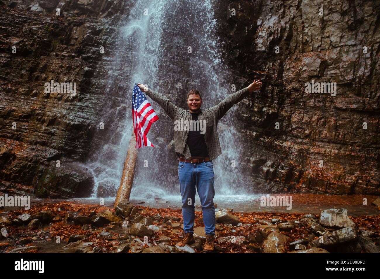 Mann mit USA-Flagge Wasserfall im Hintergrund Stockfoto