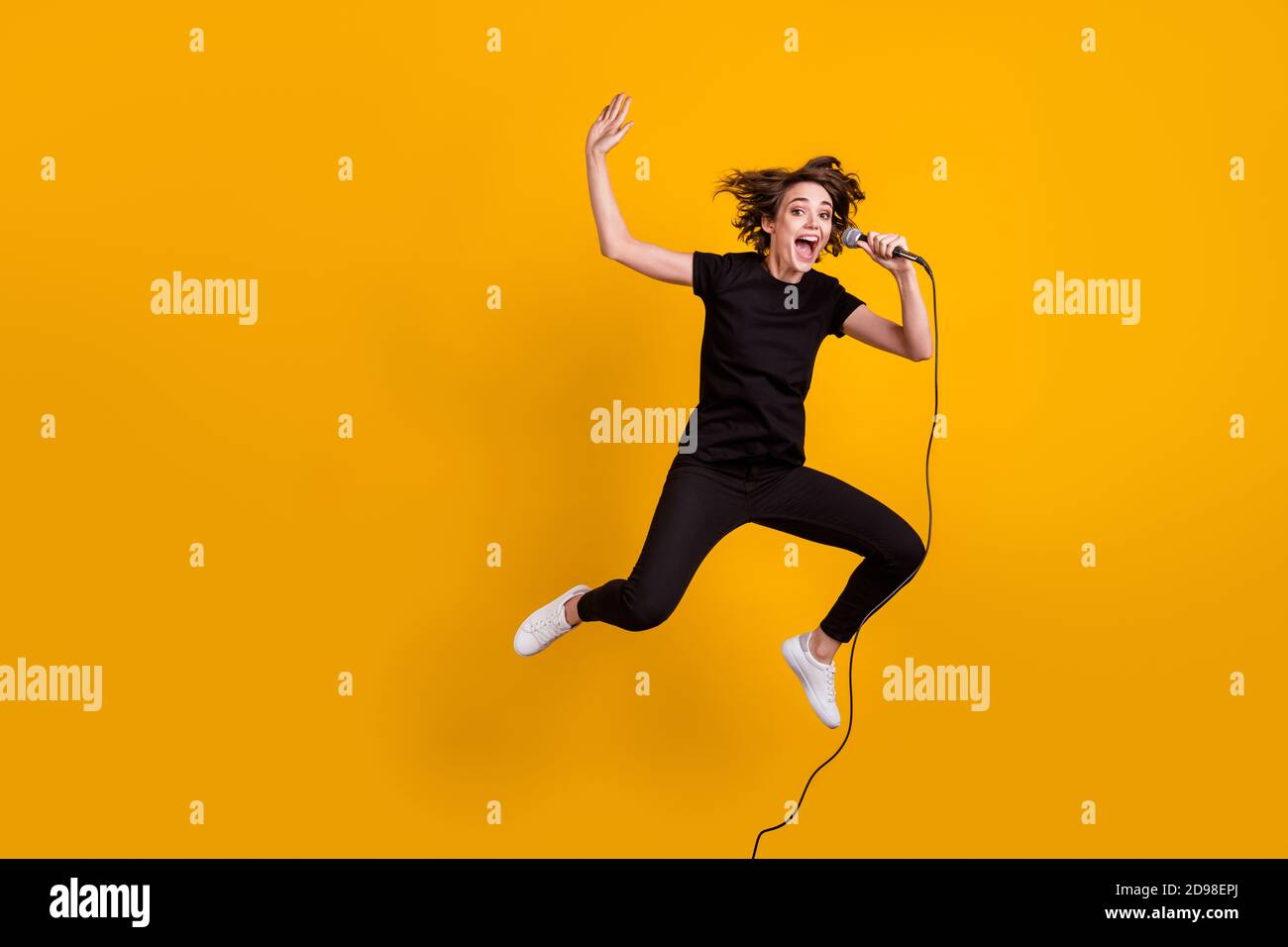 In voller Länge Körpergröße Ansicht von ziemlich fröhlich funky dünn Mädchen Künstler springen Singing Rock isoliert helle gelbe Farbe Hintergrund Stockfoto