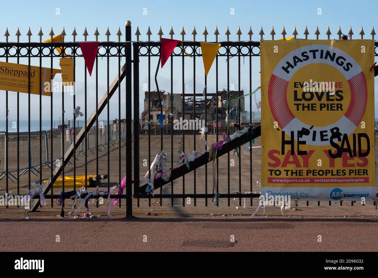 Bänder und ein verfärbtes gelbes Banner, das an die verschlossenen Tore des Hastings Pier in East Sussex, England, Großbritannien, im Mai 2011 gebunden war, sieben Monate nach einem verheerenden Brand. Der 1872 eröffnete viktorianische Pier beherbergte in den 1960er Jahren große Rock- und Pop-Acts, darunter Pink Floyd, Jimi Hendrix, die Rolling Stones und The Who. Das Feuer zerstörte 2,000 den 1972-Sitzer Hastings Pier Pavillon, der Pier wurde als gefährliches Bauwerk geschlossen und am 5. Oktober 2010 zerstörte ein Brand die verbliebenen Holzgebäude. Der Wiederaufbau wurde 2011 begonnen und die Pier wurde 2016 wieder eröffnet. Stockfoto