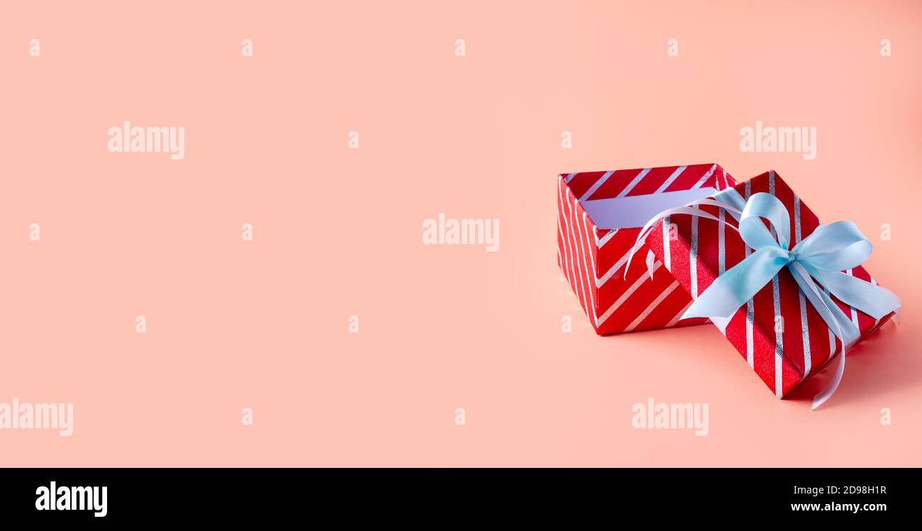 Weihnachtsrot gestreifte Geschenkbox auf rosa Hintergrund. Kreative Minimal Komposition. Banner Stockfoto