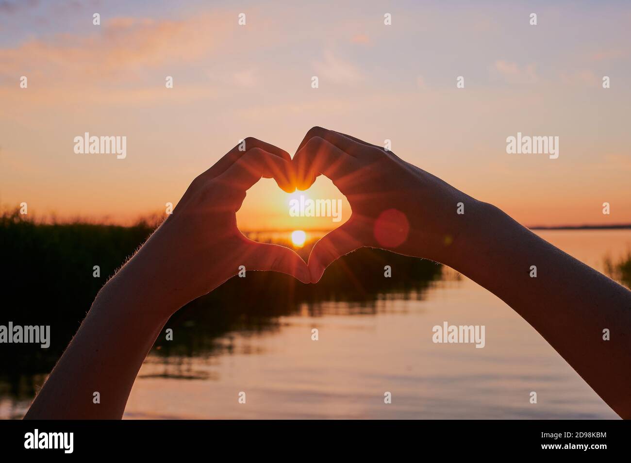 Kind bildet ein Herz um die Sonne, vor dem Chiemsee bei Sonnenuntergang Stockfoto