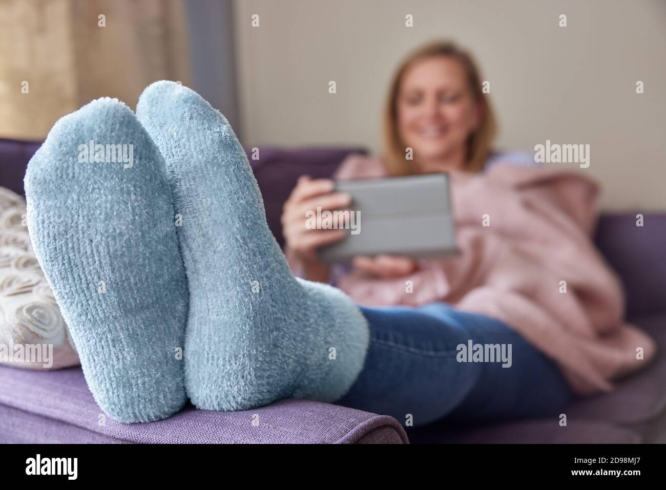 Frau Zu Hause Trägt Gemütliche Warme Socken Und Eingewickelt Decke Liegt Auf Sofa Beobachten Digital Tablet Stockfoto