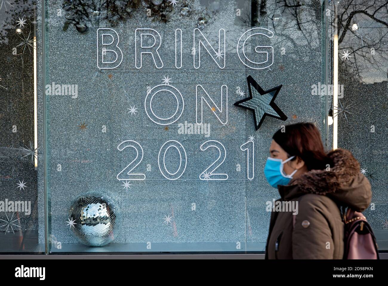 St Andrew Square, Edinburgh, 3. November 2020. Frau mit Gesichtsmaske geht an einem Schild im Fenster von Harvey Nichols vorbei, auf dem steht: 'Bring On 2021'. Stockfoto