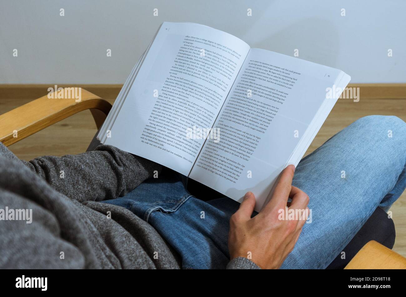 Ein männlicher Student liest ein Buch und notiert sich. Kaffee und Bücher auf dem Schoß. Über die Schulter. Stockfoto