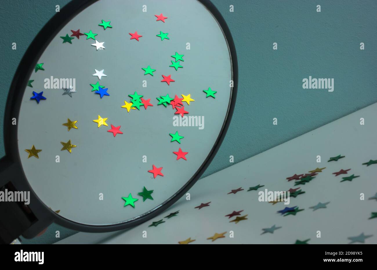 Konfetti von bunten Sternen in einem runden Spiegel reflektiert, festlichen Hintergrund Stockfoto