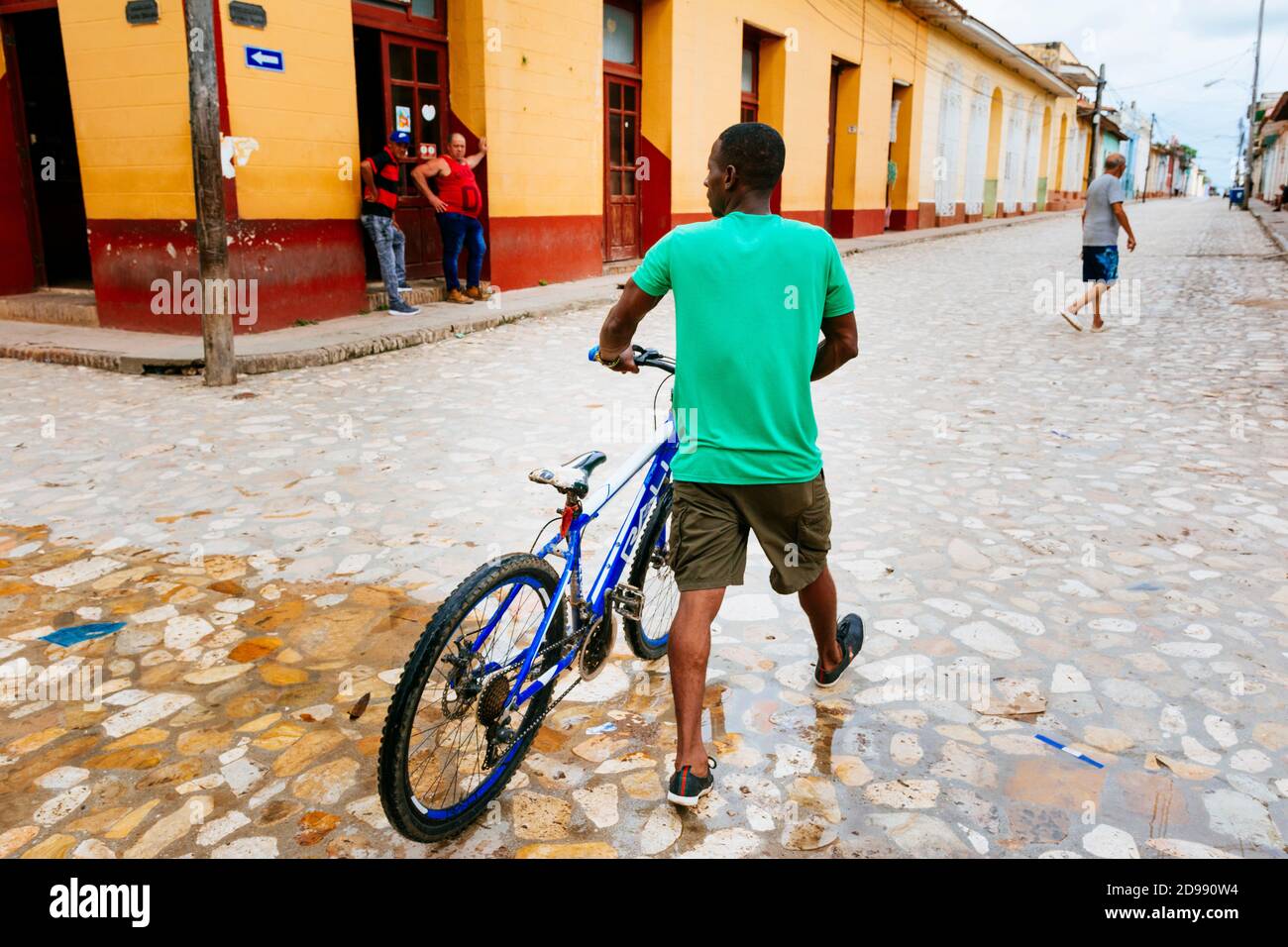 Ein Mann mit dem Fahrrad geht durch das historische Zentrum von Trinidad, Sancti Spíritus, Kuba, Lateinamerika und der Karibik Stockfoto