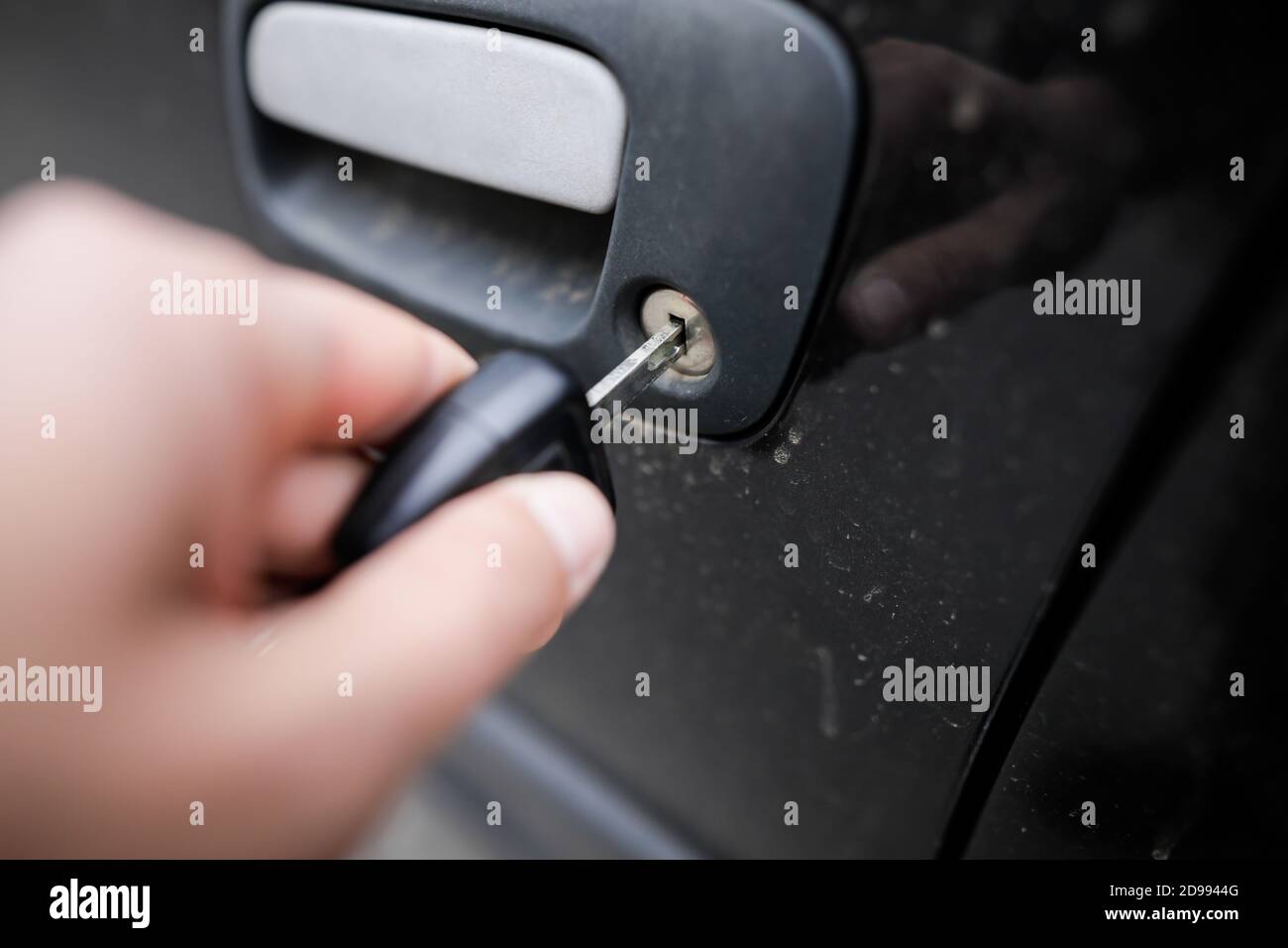 Bild mit geringer Schärfentiefe (selektiver Fokus), bei dem die Hand eines Mannes mit dem Autoschlüssel ein Gebrauchtwagen öffnet. Stockfoto