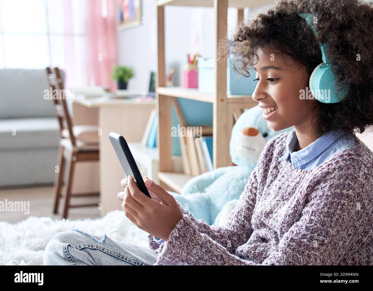 Happy african Kind Mädchen trägt Kopfhörer Video Telefonieren im Schlafzimmer. Stockfoto