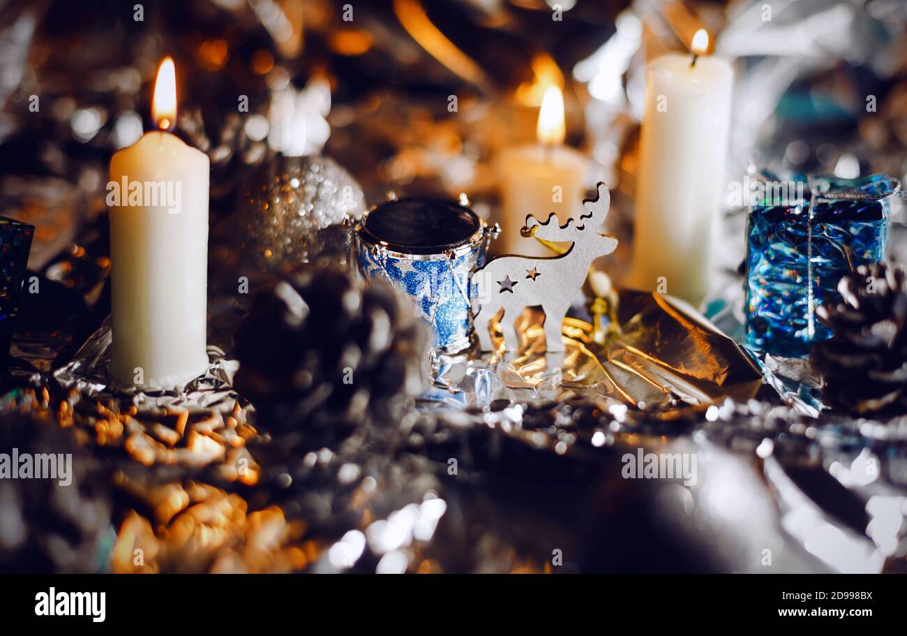 Magisches Hirsch, das in der Nähe einer dekorativen Trommel zwischen Pinienzapfen und brennenden Kerzen steht. Weihnachtsfeier Stockfoto