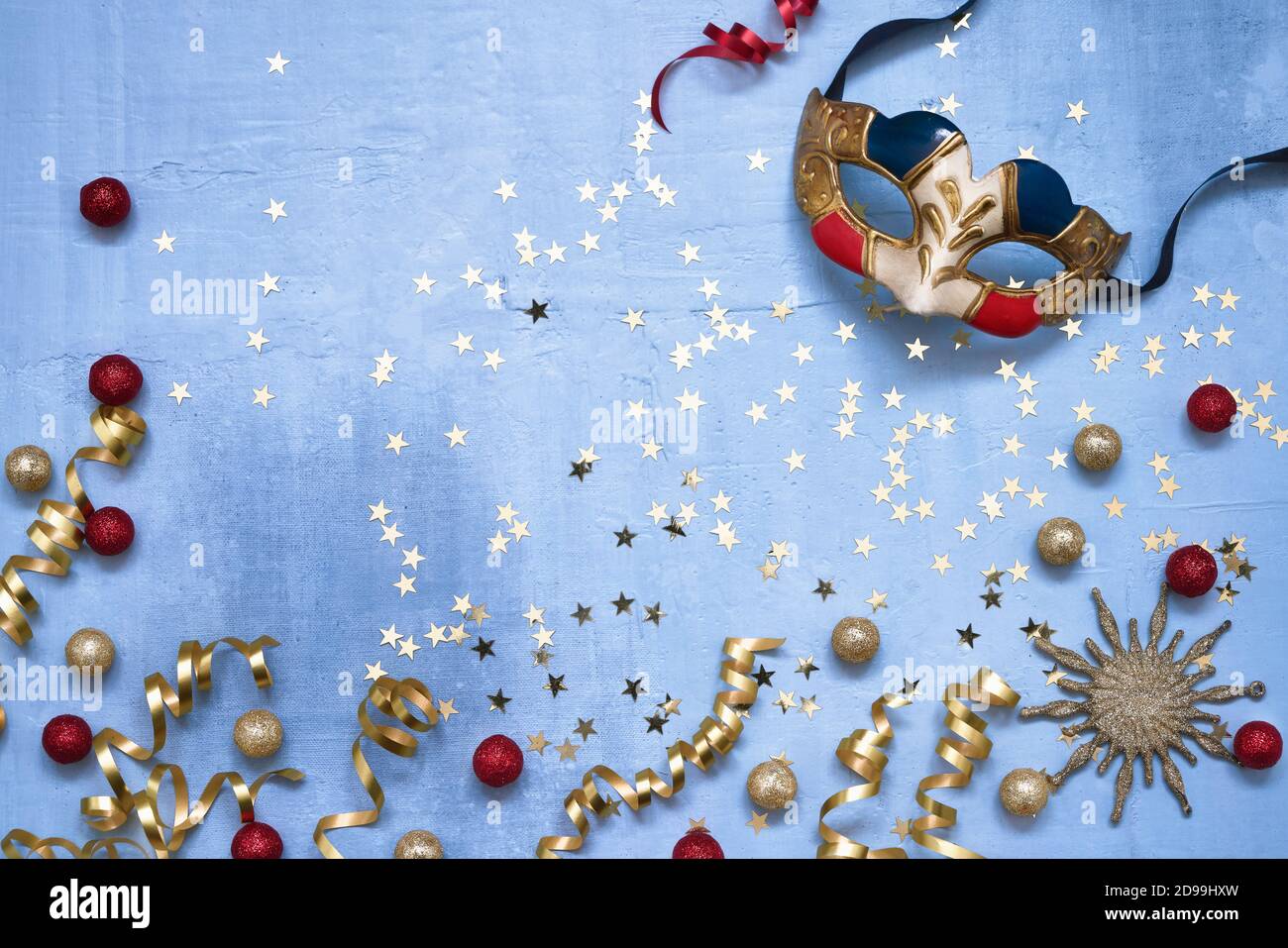 Venezianische Karnevalsmaske, Konfetti-Sterne und Party-Streamer auf blauem Hintergrund. Flaches Lay von Weihnachten, Jubiläum, Karneval, Neujahrsfeier. Stockfoto