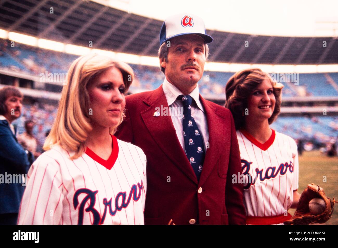 Ted Turner, Millionär-Sender und Besitzer der Atlanta Braves Baseball-Team nimmt das Feld in Atlanta Fulton County Stadium im April 1976 begleitet von hübschen "Ballgirls" und chomping auf seiner Markenzeichen Zigarre. Stockfoto
