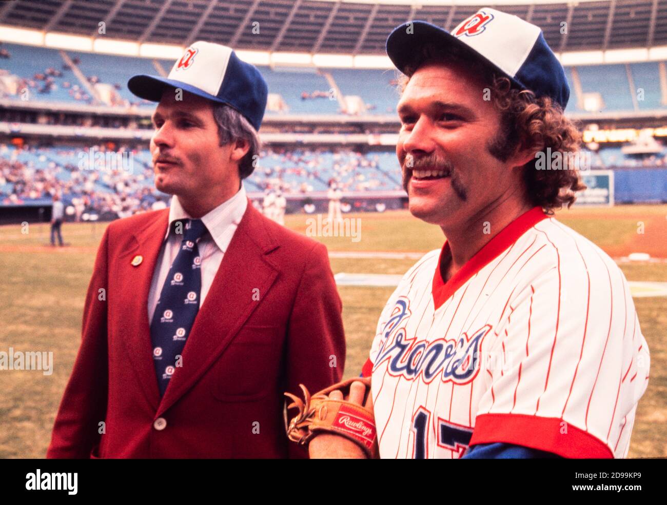 Ted Turner, Millionär-Sender und Besitzer der Atlanta Braves Baseball-Team nimmt das Feld in Atlanta Fulton County Stadium im April 1976 begleitet von hübschen "Ballgirls" und chomping auf seiner Markenzeichen Zigarre. Stockfoto