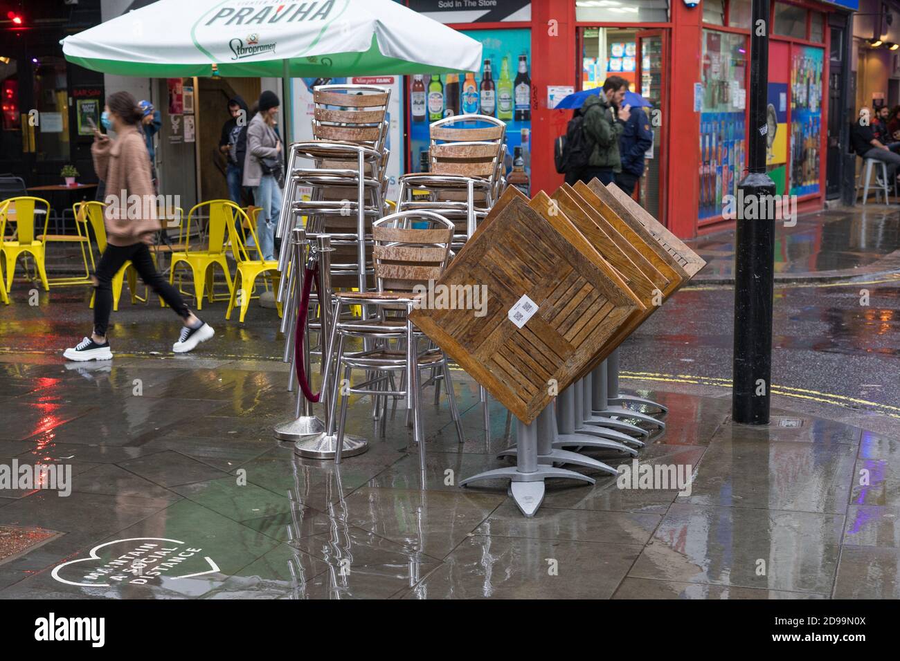 Stapel von hölzernen Restaurants Stühle und Tische im Regen auf der Straße von Soho. Old Compton Street. London Stockfoto
