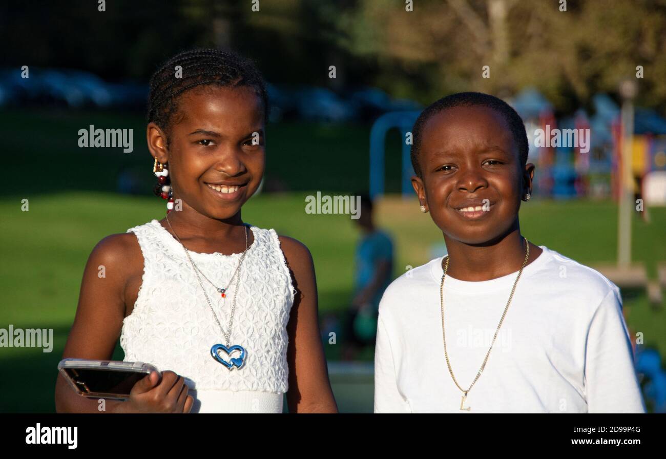Ein Porträt von zwei afroamerikanischen Kindern, 8-10 Jahre alt, alle in weiß gekleidet. Wir sind gerade von einer Hochzeit im Park zurückgekommen. Brea, CA, USA Stockfoto