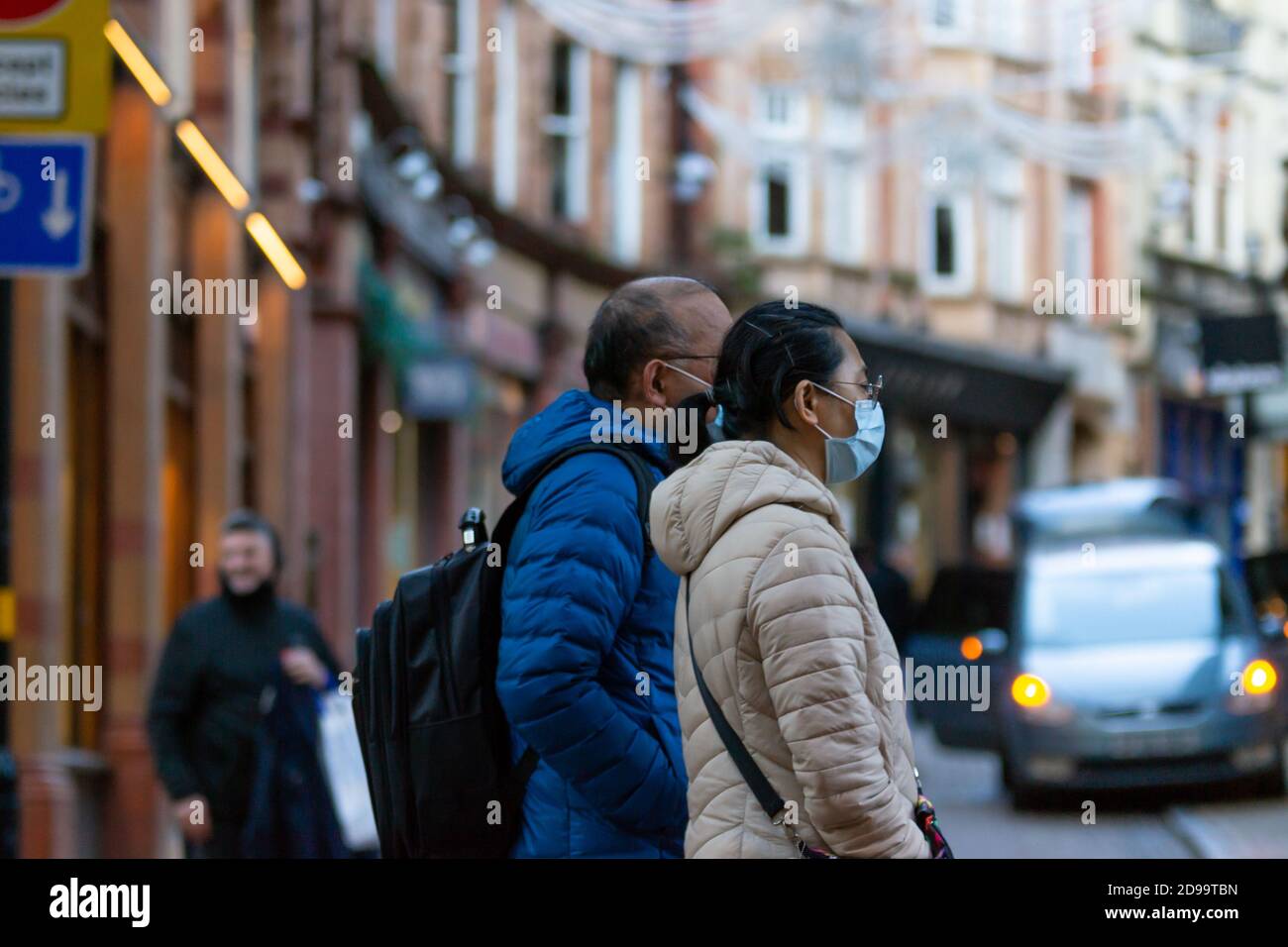 Ein paar Spaziergang entlang der New Street in Birmingham, West Midlands, Großbritannien trägt Gesichtsmasken. Das Land wurde bis Dezember in eine nationale Sperre gekehrt Stockfoto