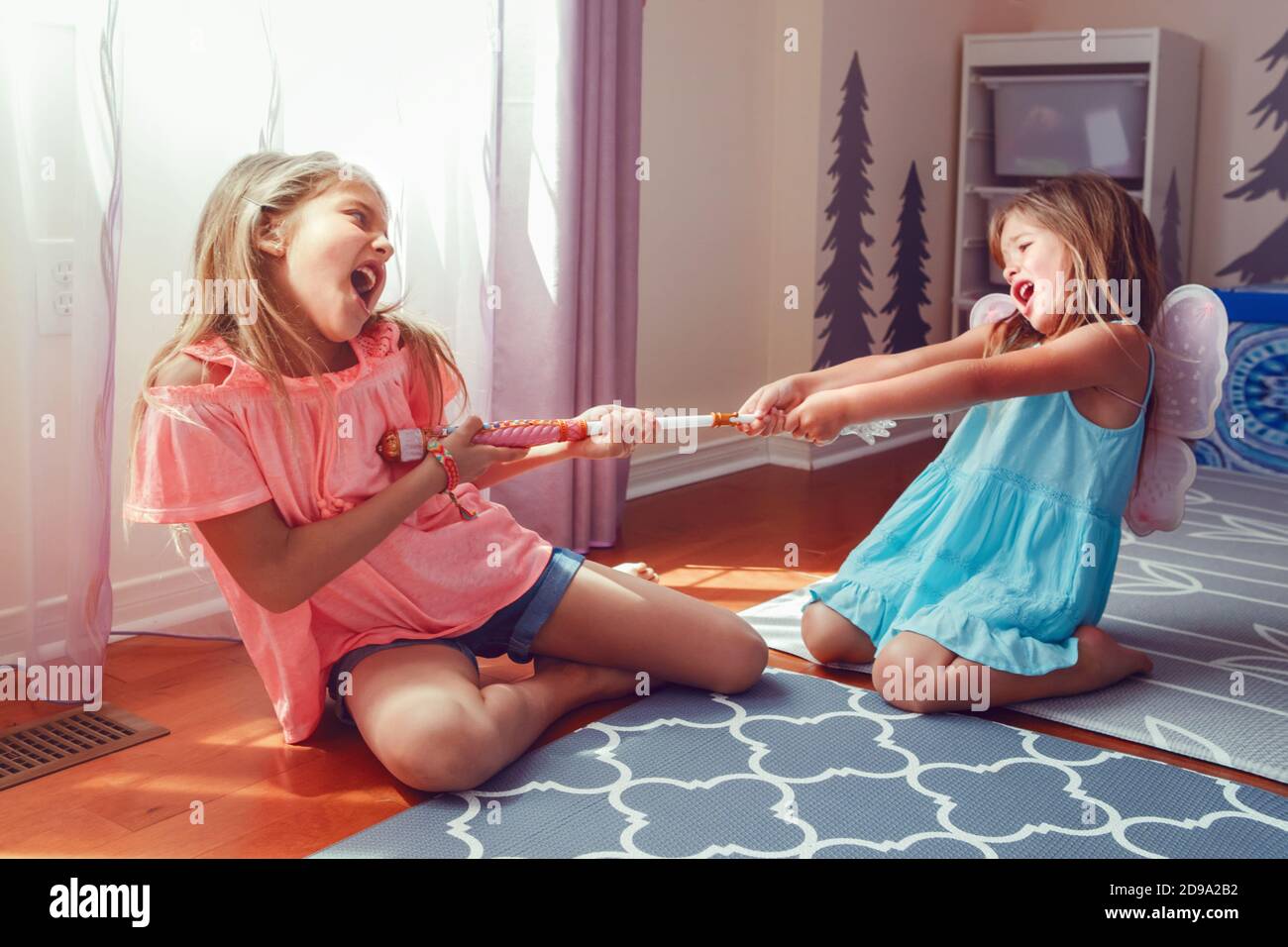 Zwei kleine verrückte Mädchen Schwestern, die zu Hause kämpfen. Freunde Mädchen können kein Spielzeug teilen. Lifestyle authentisch lustiger Familienmoment der Geschwister streitet Stockfoto