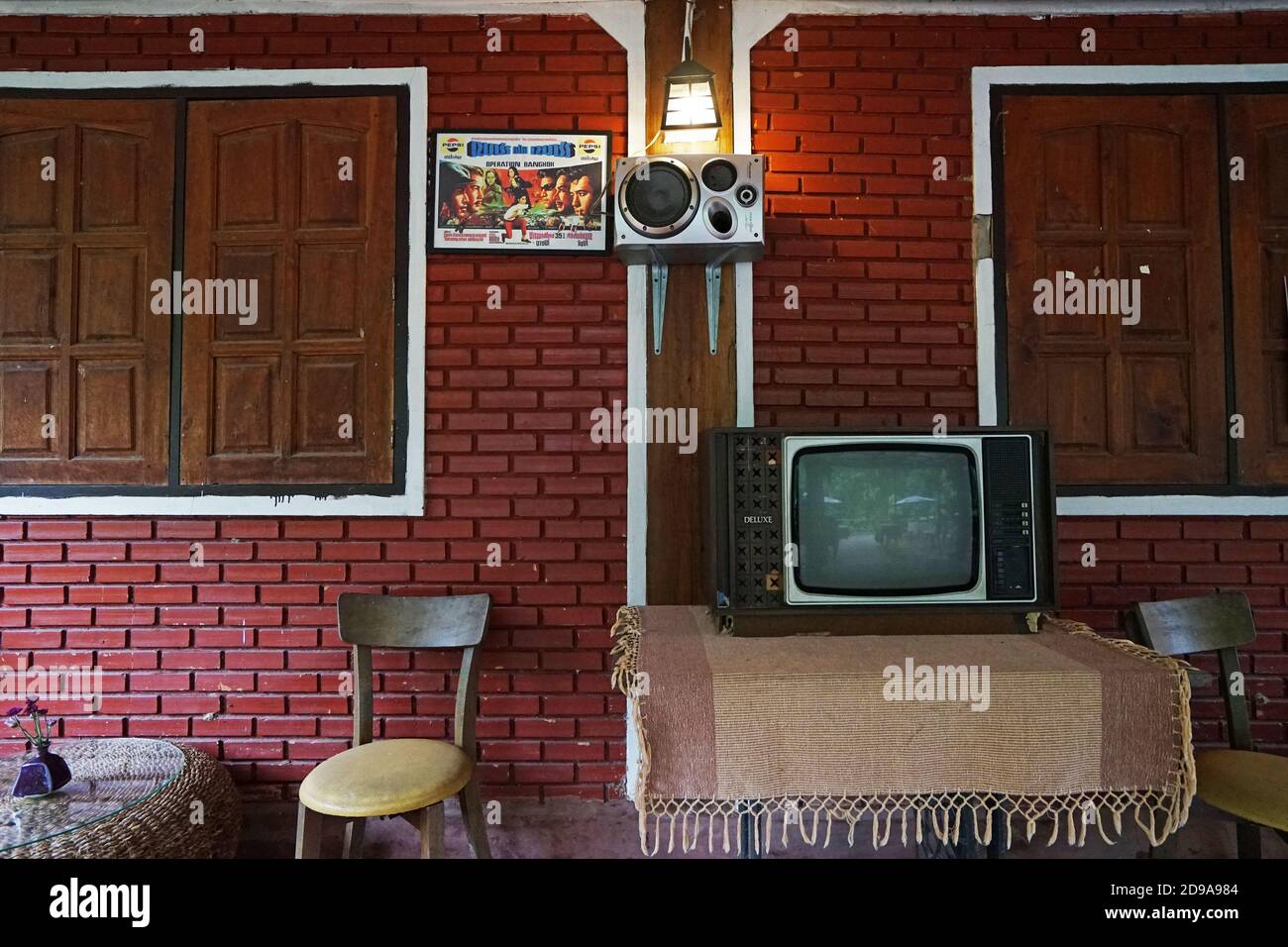 Innendesign und Dekoration der thailändischen Wohnzimmerecke mit Vintage-Fernseher, roter Backsteinwand und Holzfensterrahmen Stockfoto