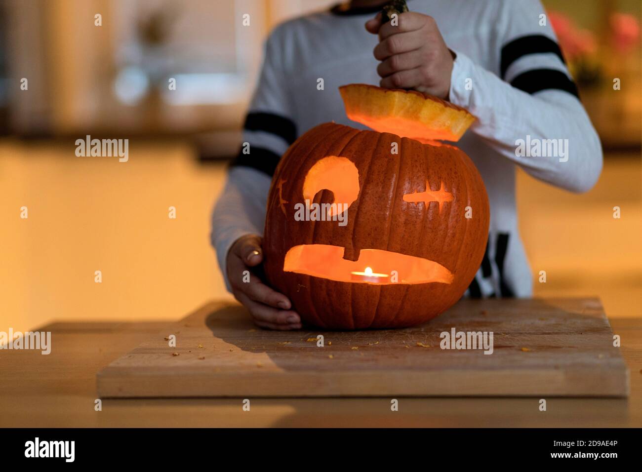 Der Junge schnitzte Halloween-Kürbis und steckte ein Kerzenlicht hinein Stockfoto