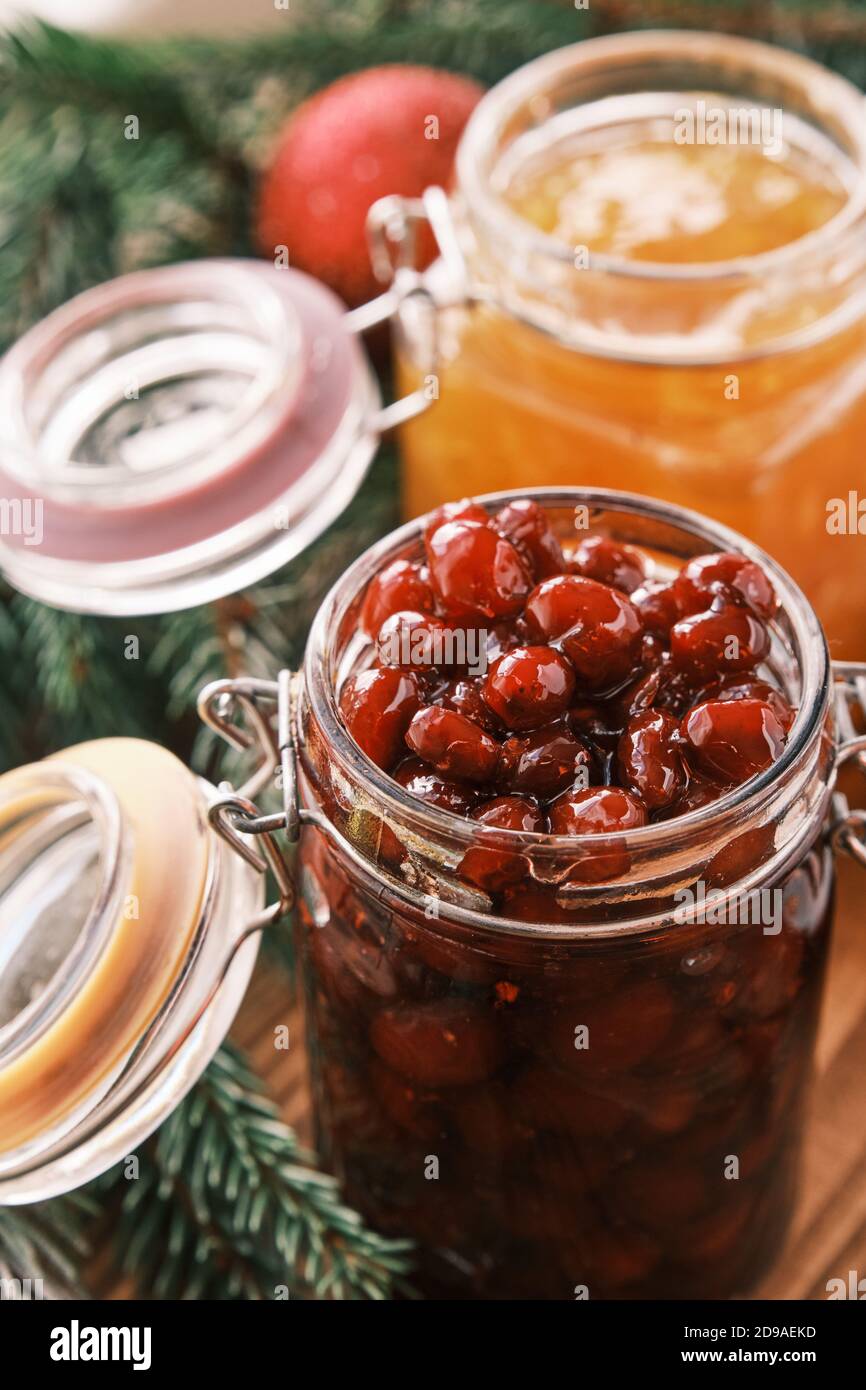 Nahaufnahme eines Orangen- und Dogwood Konfitüren Gläser auf einem Holztisch mit Apfelstrudel im Hintergrund Stockfoto