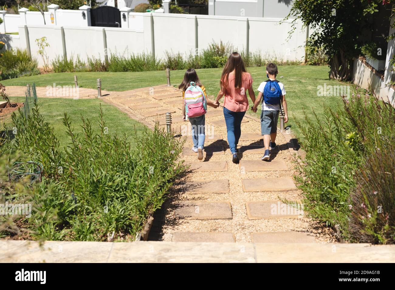 Kaukasischer Junge und Mädchen, die mit ihrer Mutter zur Schule gehen Stockfoto