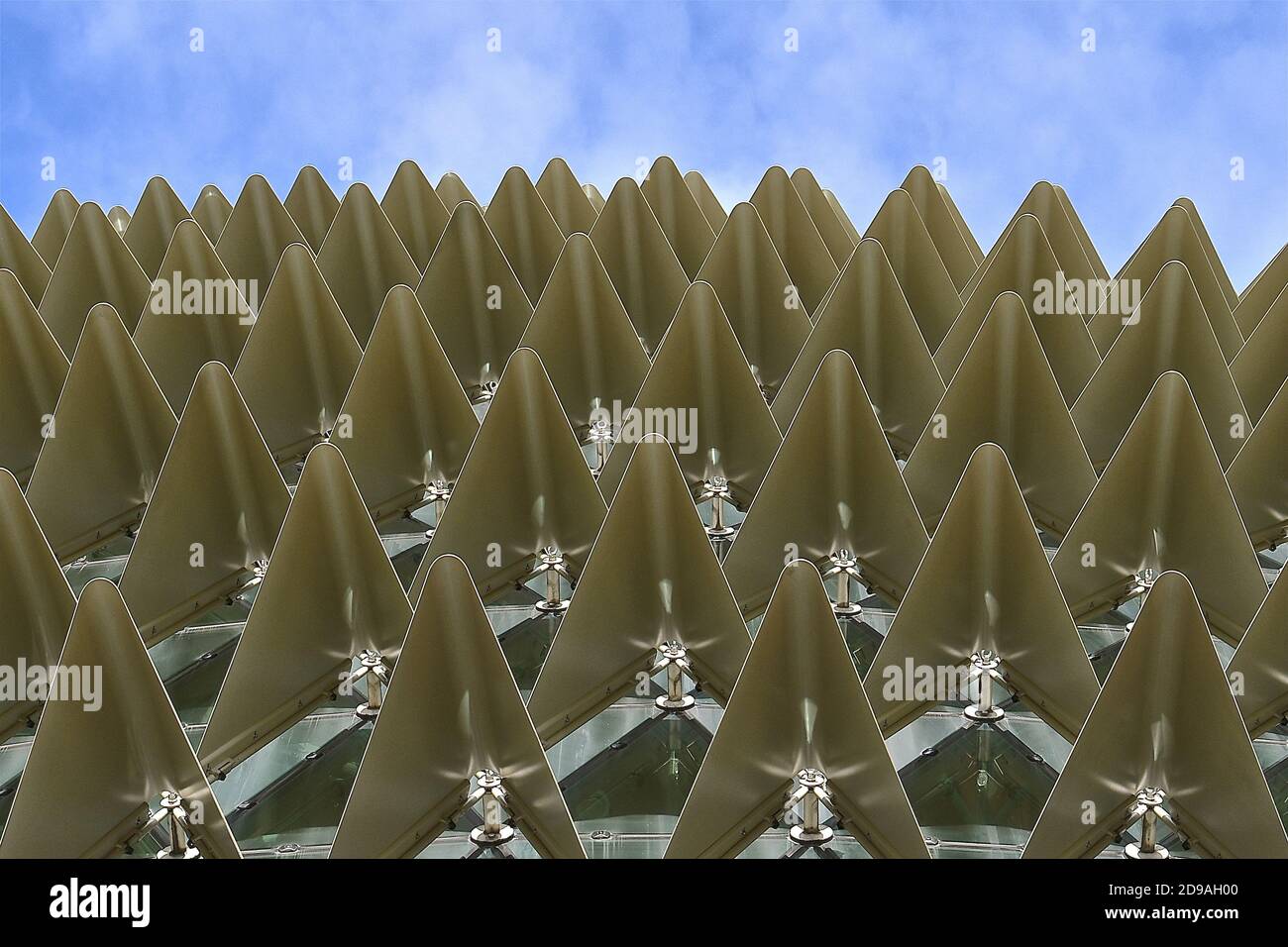 Nahaufnahme der Reihen von gefalteten metallischen goldenen Dreiecken vor einem blauen Himmel Hintergrund. Stockfoto