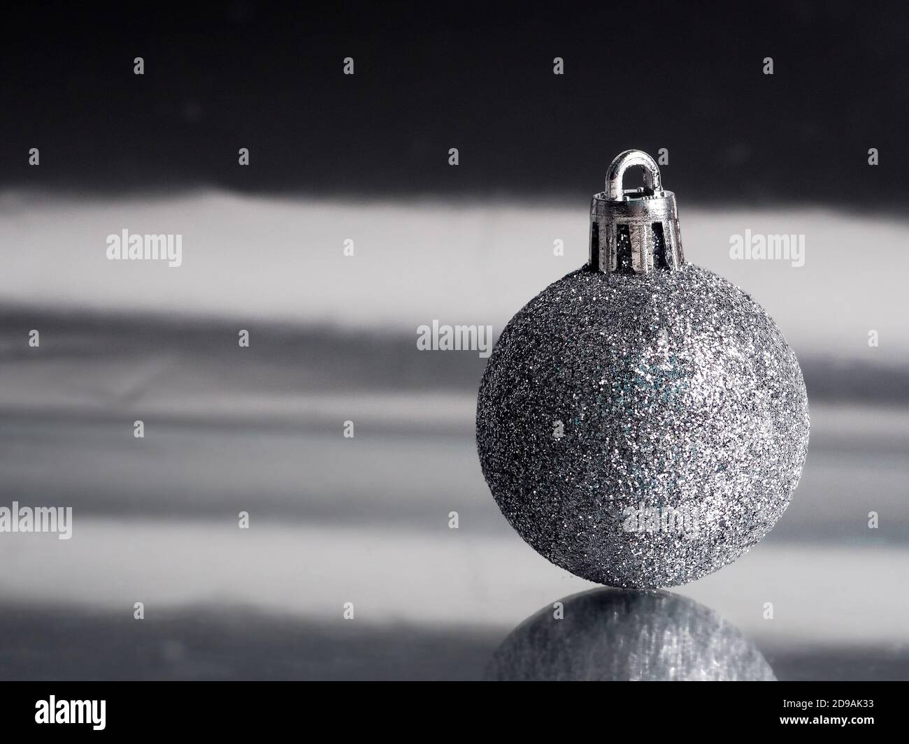 Silberner Ball auf Hintergrund mit Reflexion, Minimalismus Weihnachten. Stockfoto